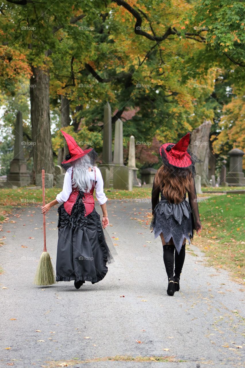 Witches walking through the cemetery in autumn