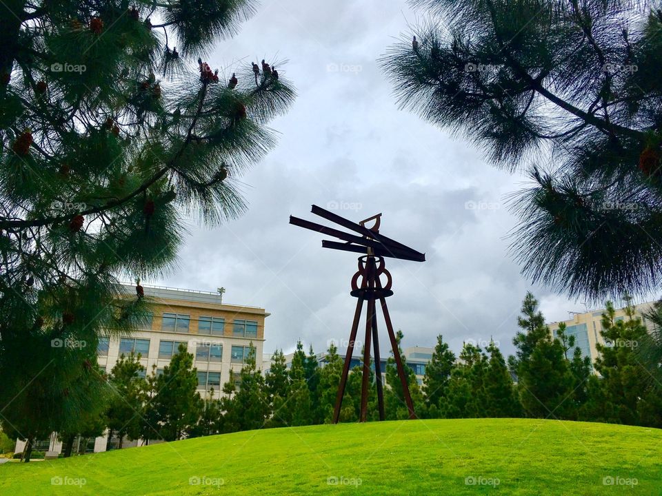 This photo of a giant, rusty sculpture on the Mission Bay campus of UCSF looks almost apocalyptic, with the cloudy sky and view between the pines. 