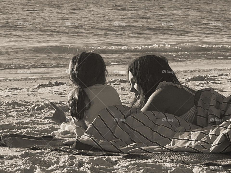 Siblings sharing stories on beach blanket 