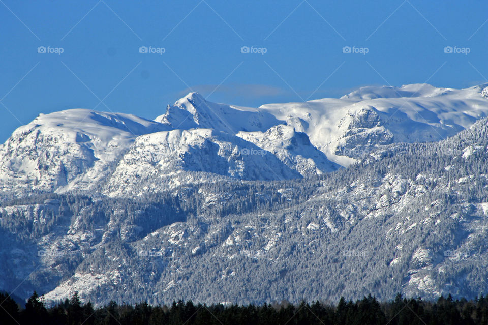 It was a beautiful sunny winter day which is rare on the Pacific North ‘wet’ Coast. It was relatively cold for our standards & cloudless which made for some awesome mountain vistas. This shot was taken from a waterfront pier & zoomed in on the peaks.