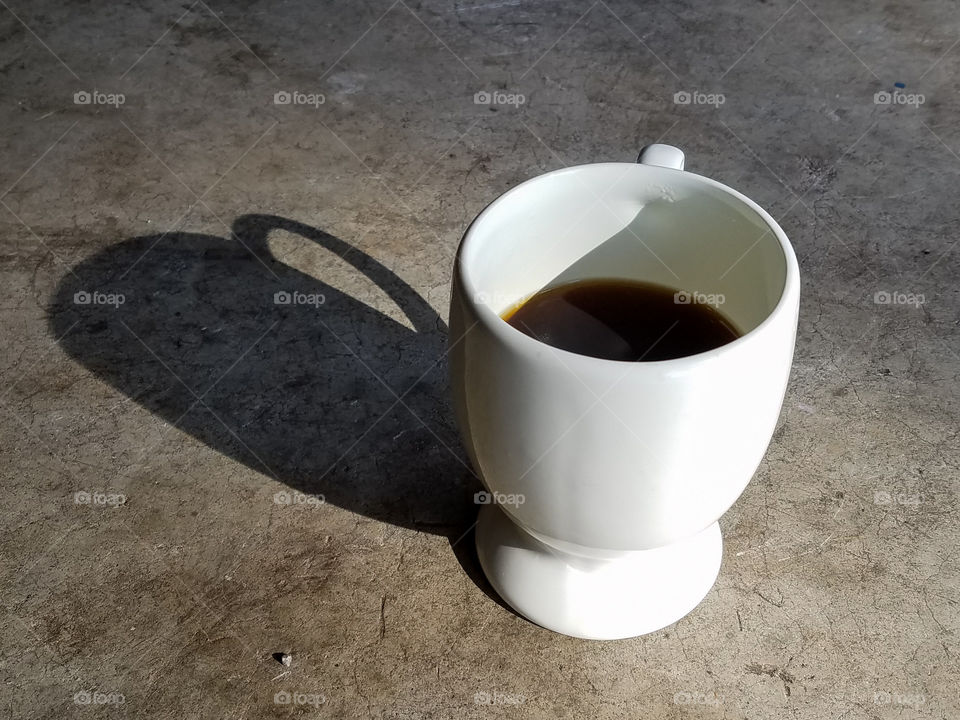 mug with coffee in it casting a shadow.