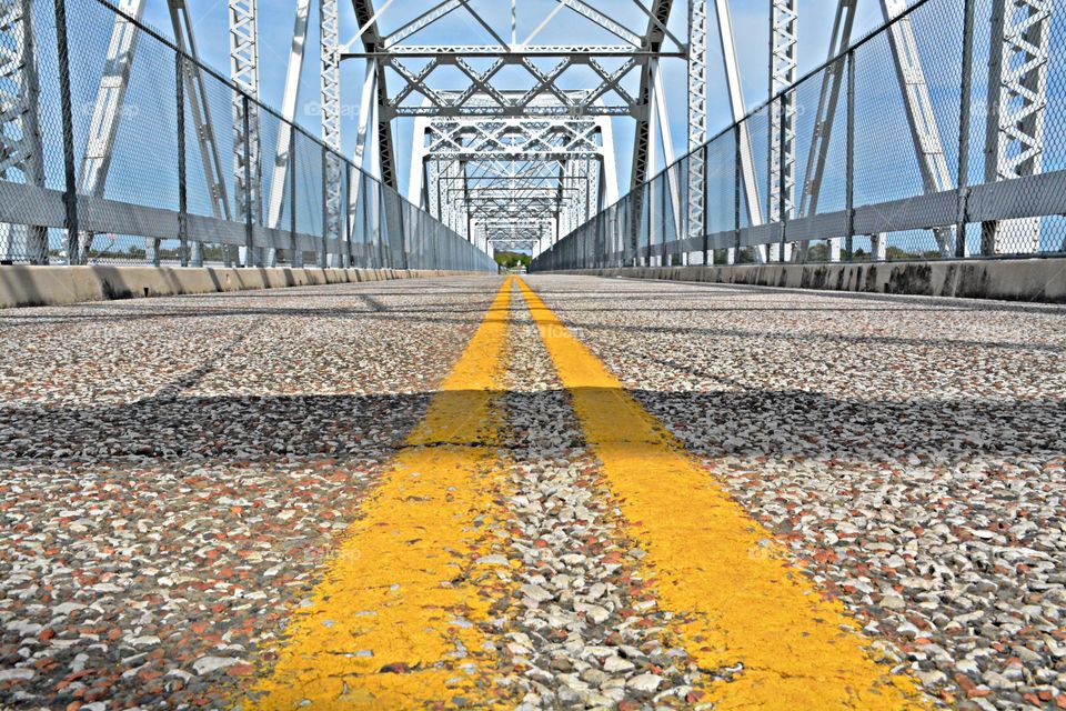 
Symmetry - A symmetrical ground level view of yellow stripes on the roadway on a bridge. Symmetry is important in bridge design because the entire length of the bridge must be able to bear  heavy weights 