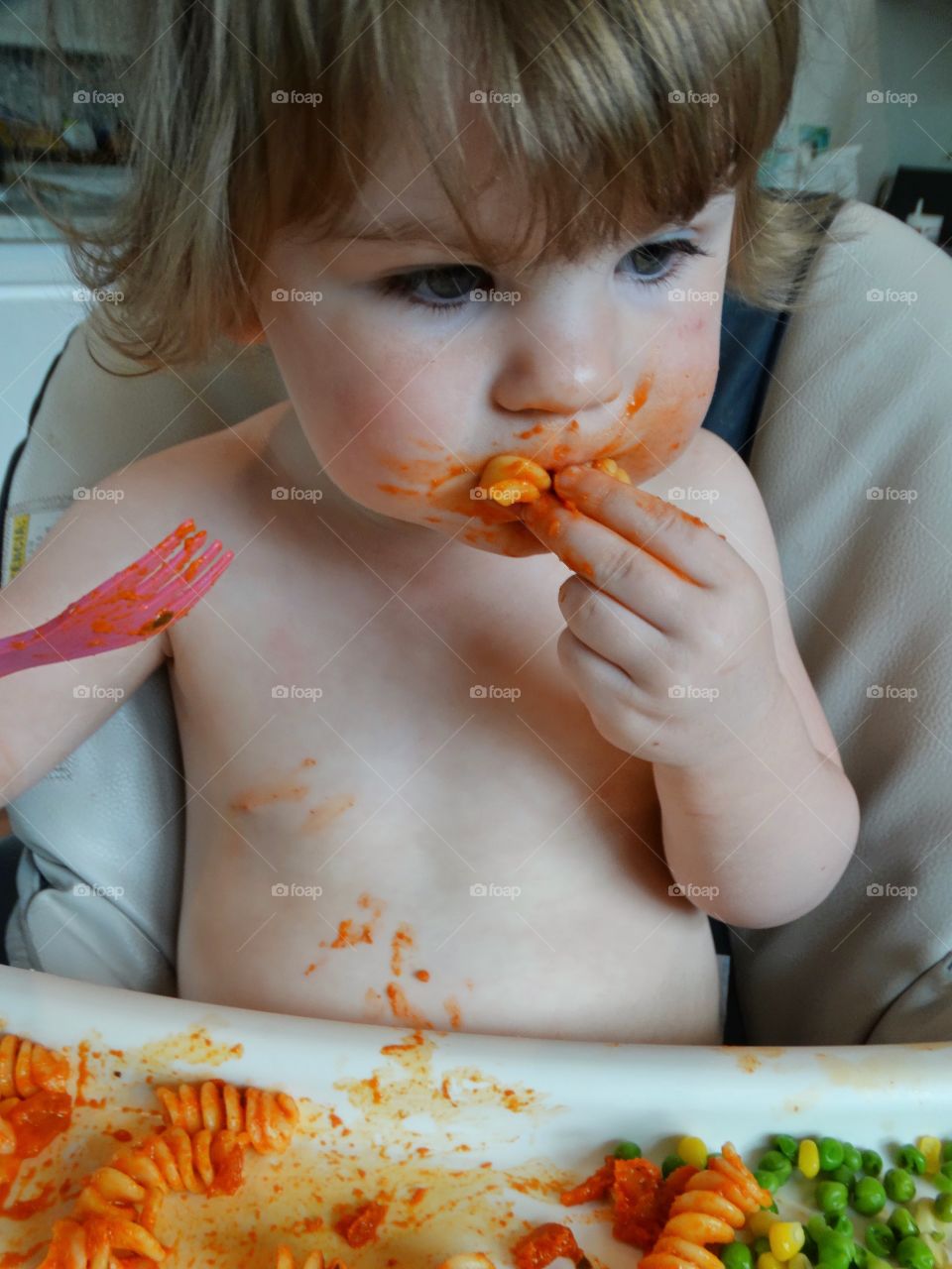 Messy Toddler Eating In A Highchair