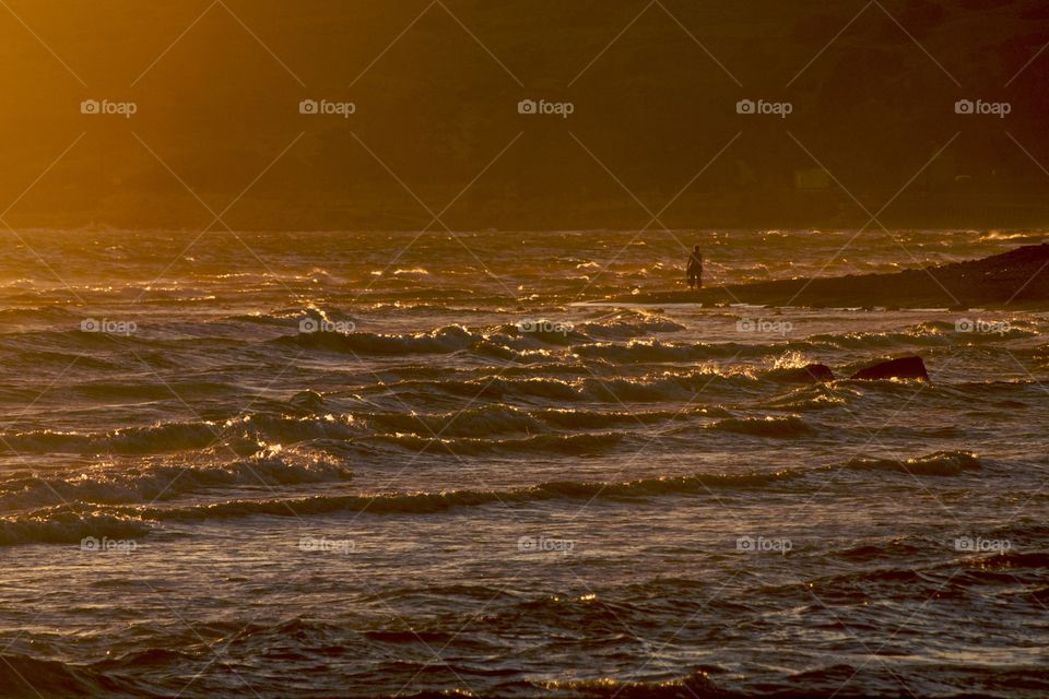 Lady walking along the shore at sunset