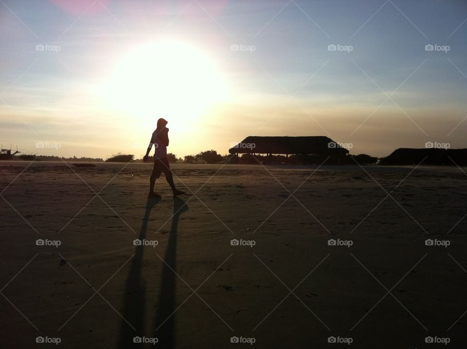 Man walking by a beach rubbing his nose