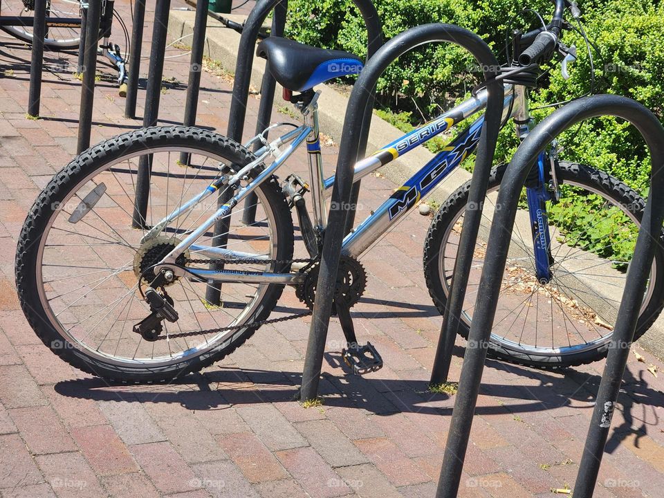 racing bicycle parked at bike rack on brick walkway