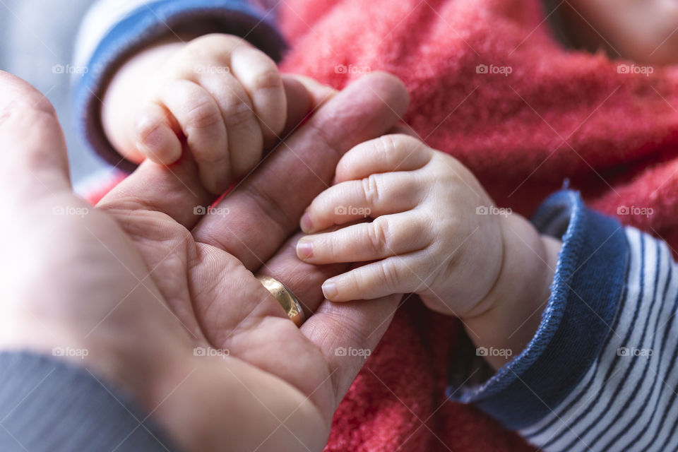 A portrait of the hand of a father being grabbed by the small hands of a baby girl. Truly something to fall in love with.