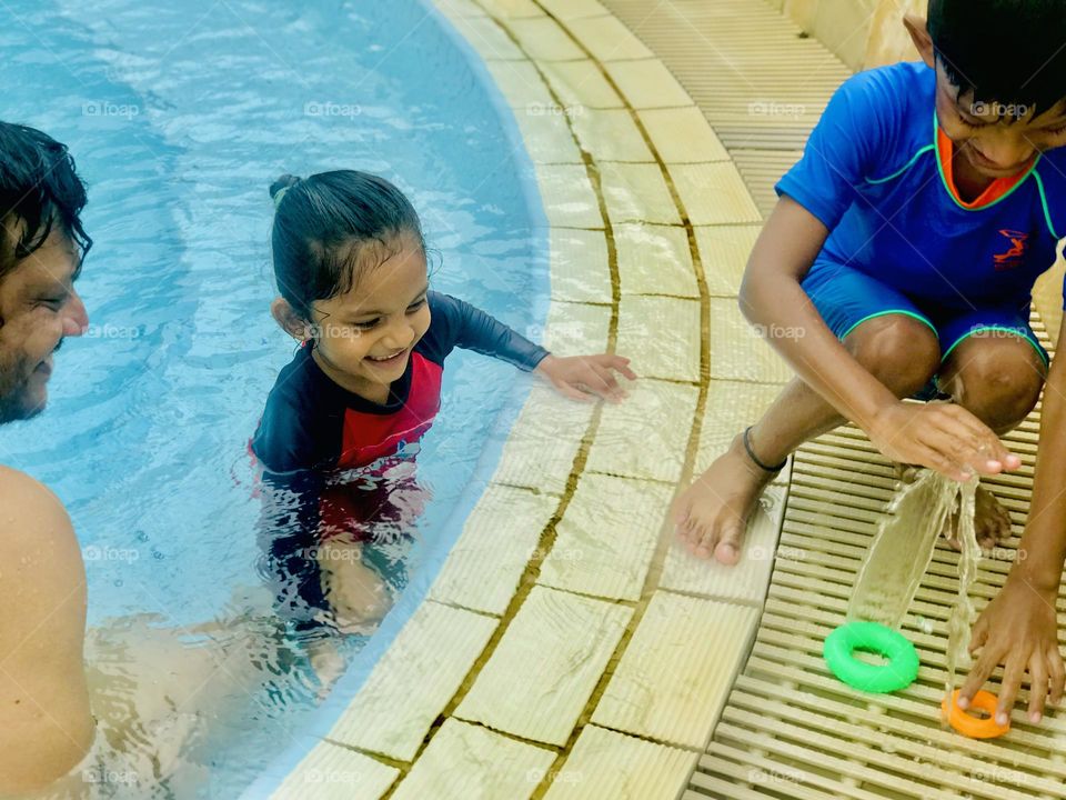 Father and kids enjoying at swimming pool and everyone feels so happy and smiling 