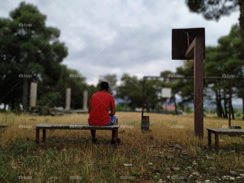 A man sits on a bench in nature