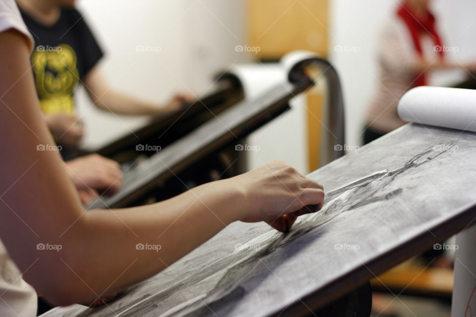 An artist works on a charcoal drawing in the studio