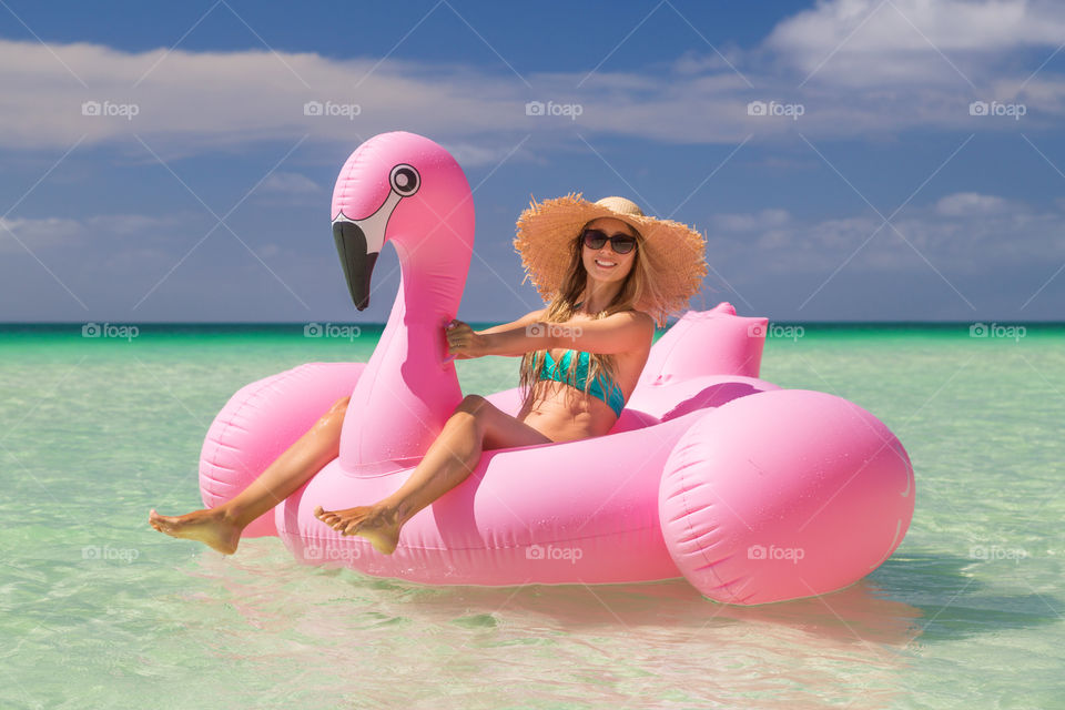 Happy woman relaxing on inflatable flamingo 