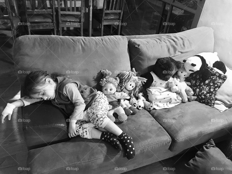 Sleeping girl on the couch with all her dolls and bears