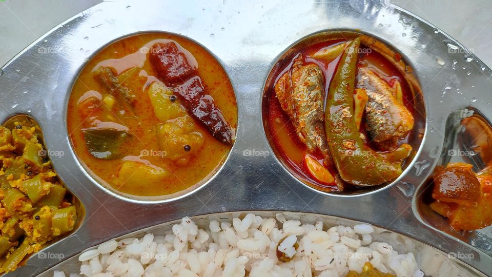 Sambar and fish curry, spicy curry from India, Indian vegetarian and non-vegetarian curry, food from India, Thoran(left end) and lemon pickle (right end)