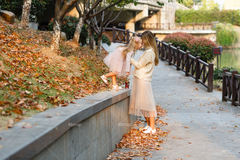 Stylish mother and daughter in autumnal park 