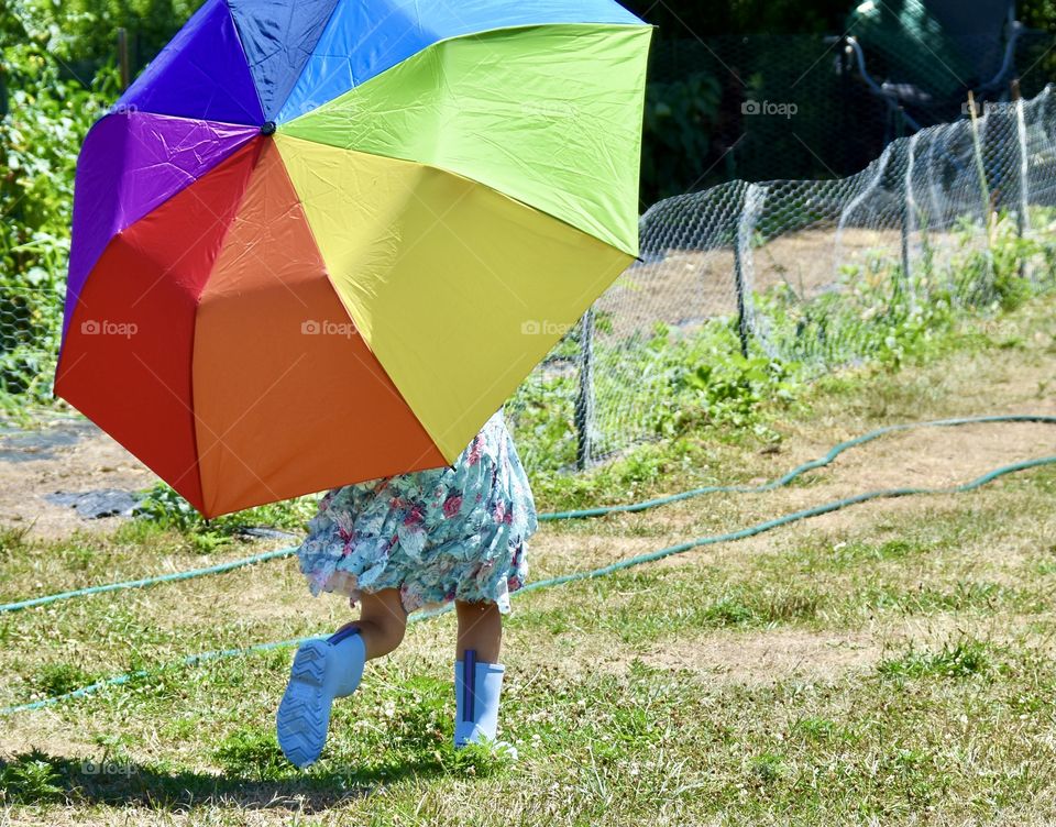 Little girl running with a colorful umbrella 