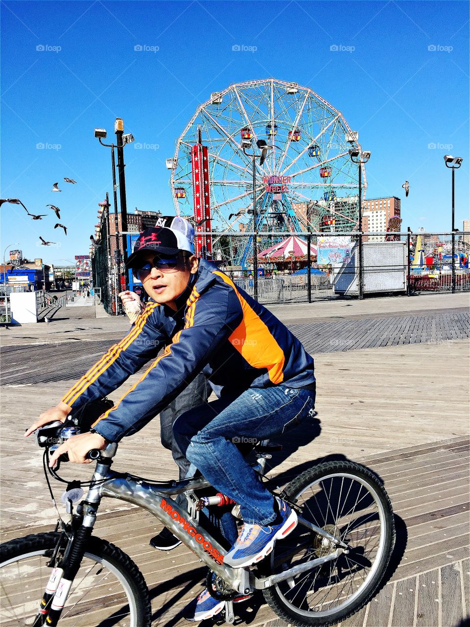 Cyclist pedal in front a amusement park in a blue sky day
