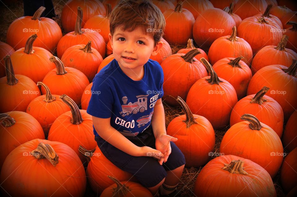Close-up of a boy sitting on pumpkin
