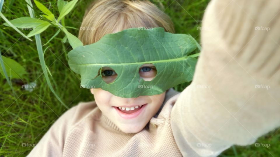 smiling little boy with a leaf on his face