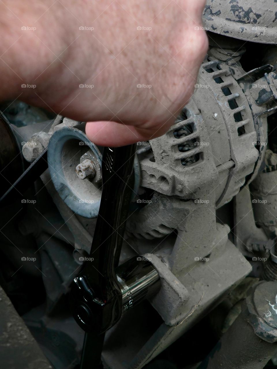 Under the hood of a red pickup truck with wrench tool and the mechanic handyman fixing a piece.