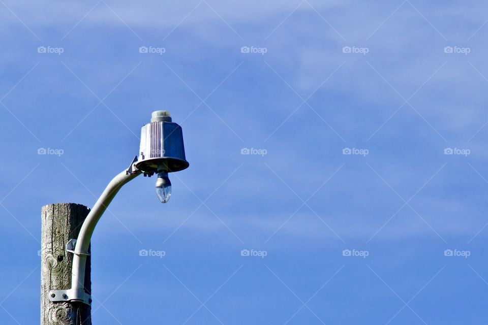 Minimalistic shot of a vintage yard light against a bright, blue sky  