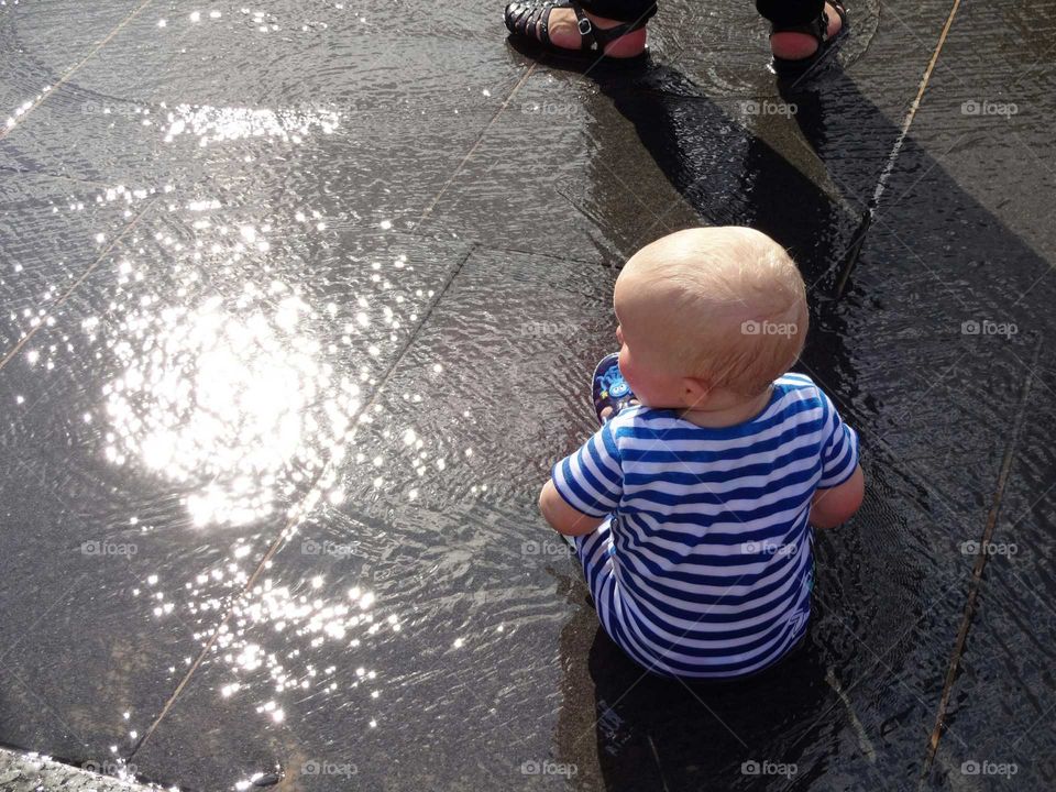 Young boy sitting in fountain square in city centre of Nottingham, England