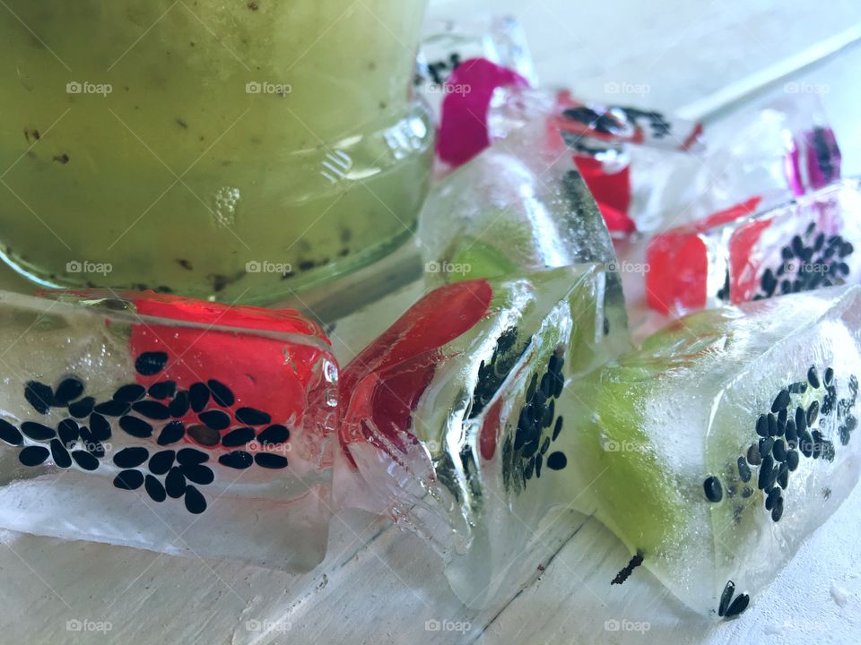 Kiwi juice and aromatic ice with fruit and flower petals