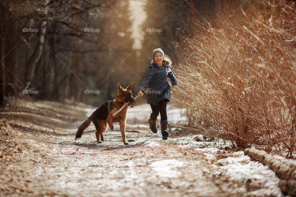 Girl walking with German shepherd puppy in a spring forest 