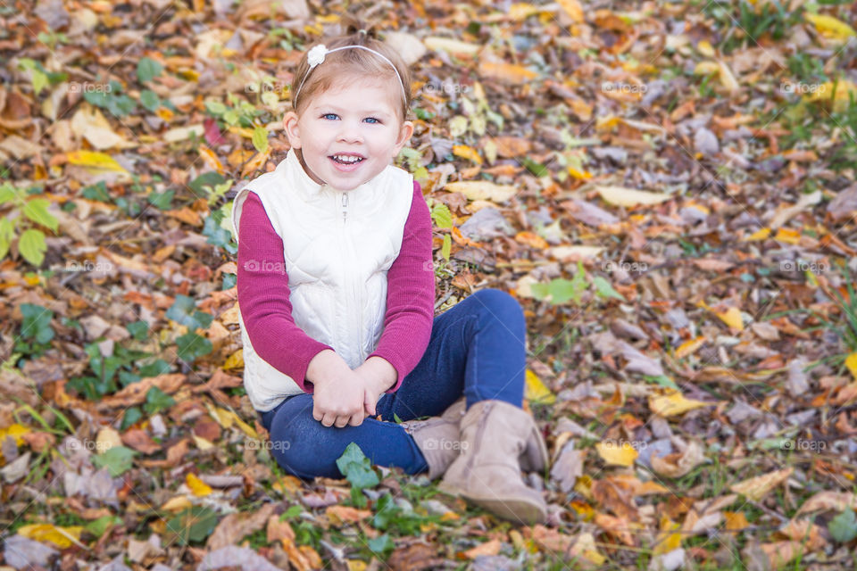 Happy girl sitting on autumn leafs