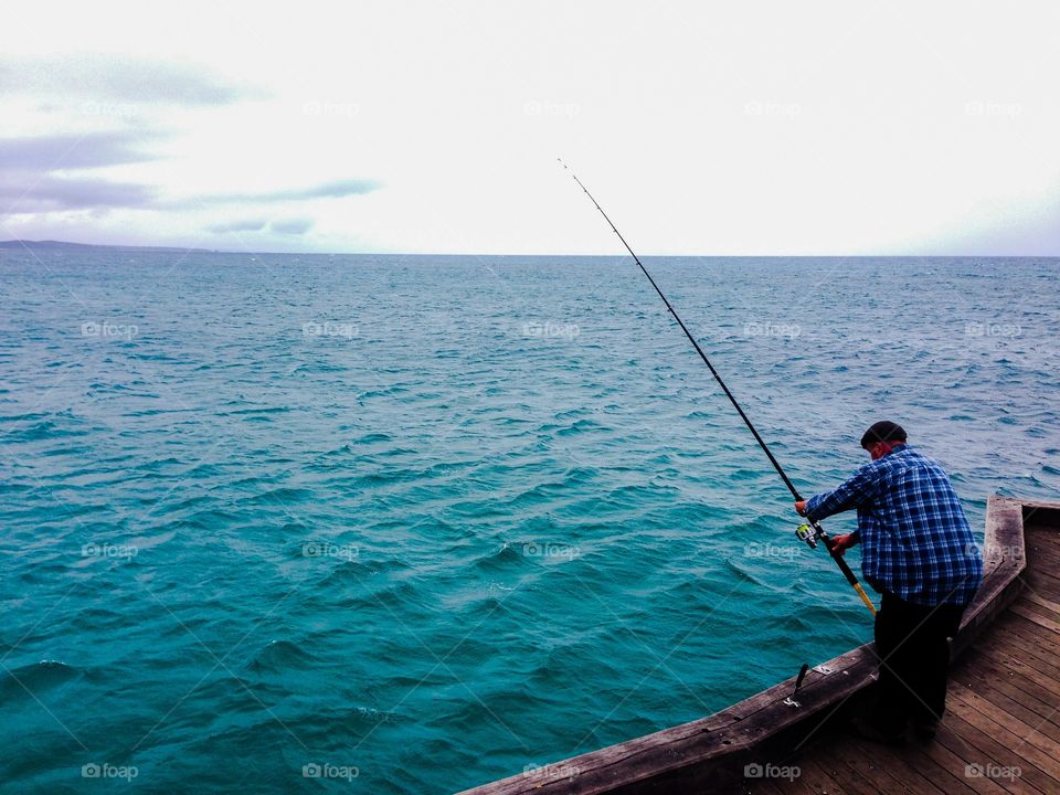 Fishy business. Man fishing at Lorne Pier, Victoria, Australia