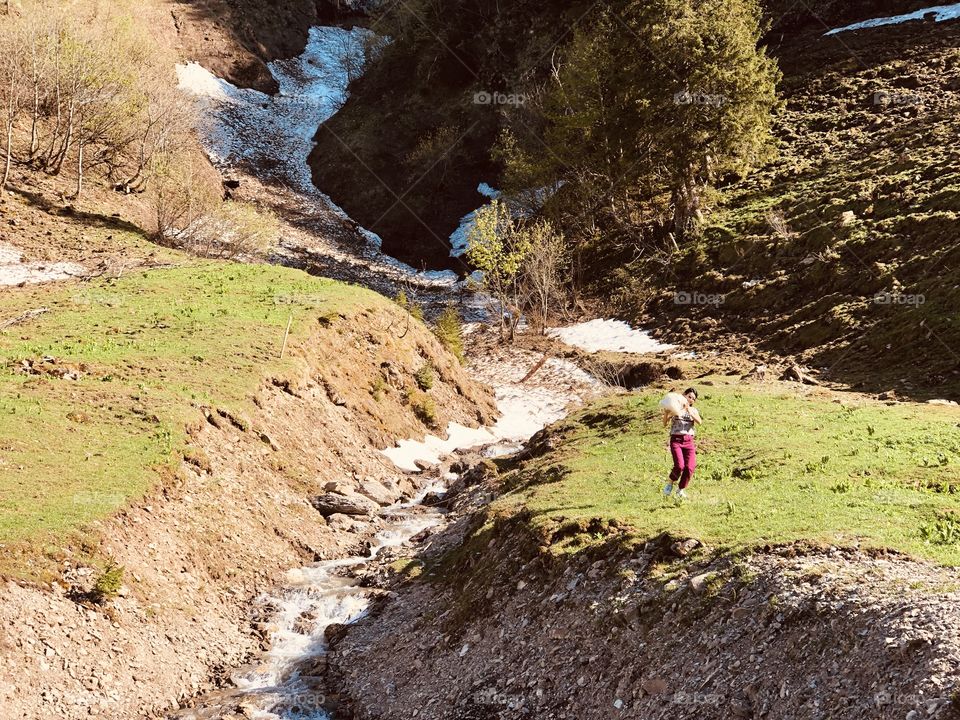 water flows, stream, waterfall, snow in the mountains, laughter, snow in hands, snow in holes, green grass, spring