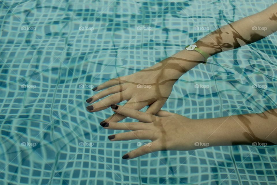 Hands under pool water