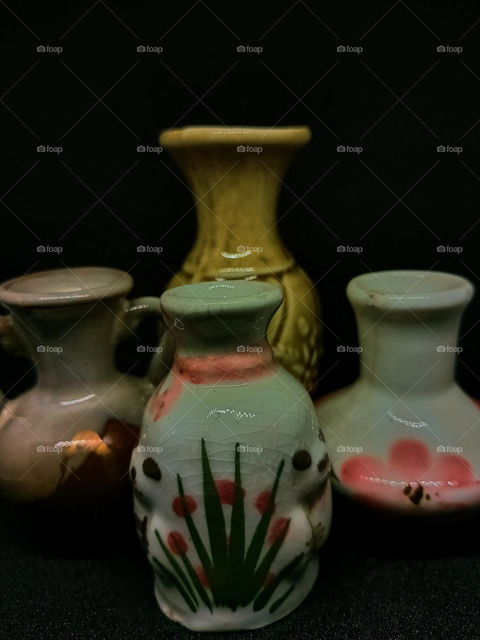 Still life with Variations of earhenware Pot and bottles isolated on black background