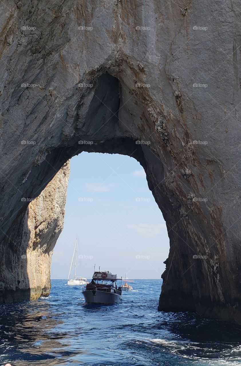 barco a través de un arco natural en las cercanías a la bella isla de Capri