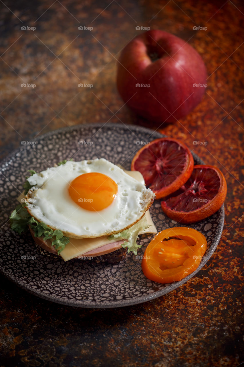 Sandwiches with fried egg orange tomato and red orange fruit 