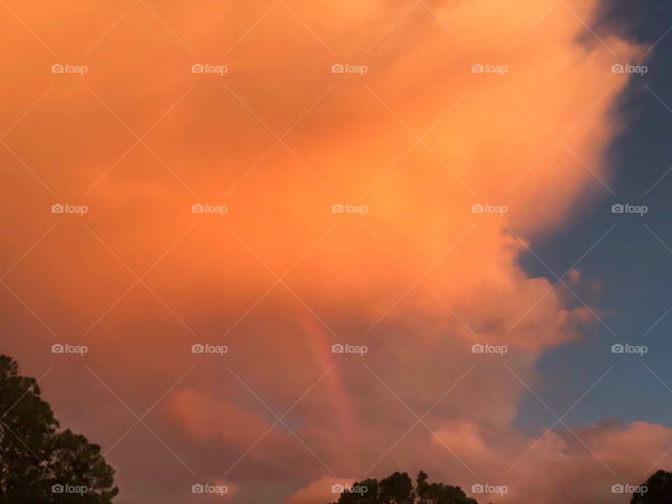 Orange sunset and a rainbow after a storm.