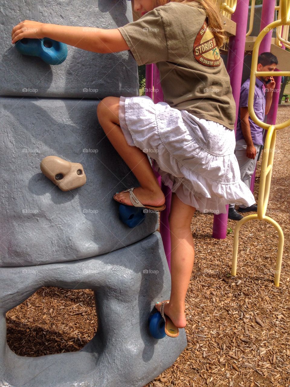 Rock climber in the making. Girl climbing the rock wall at the park