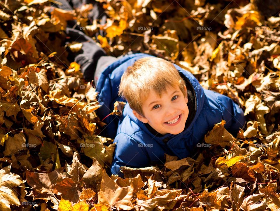 Young boy playing in leaves.