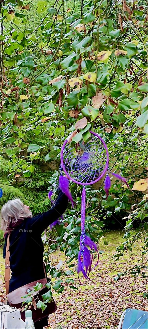 Handcrafted American Indian style dream catchers are being affixed to a tree in the garden of the old castle of “Steinach” in “Lower Bavaria”, Germany to display them for sale at the “Market of Possibilities”. 2024. Hypnotic Productions