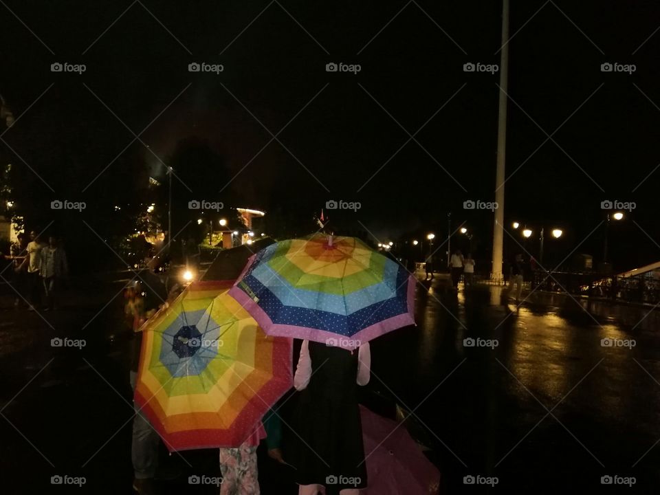 Beautiful two colorful umbrellas in city road at night.