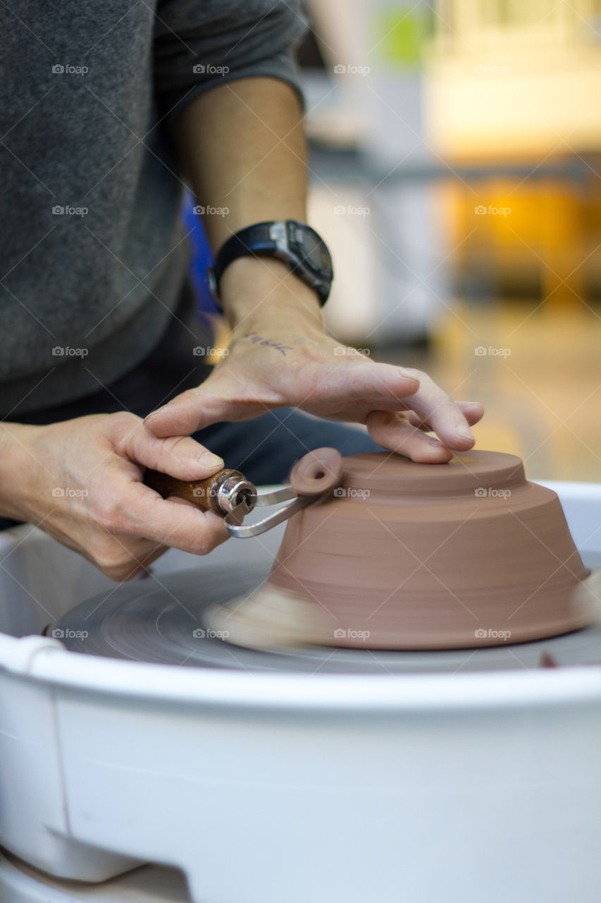 An artist works at the wheel on a piece of pottery