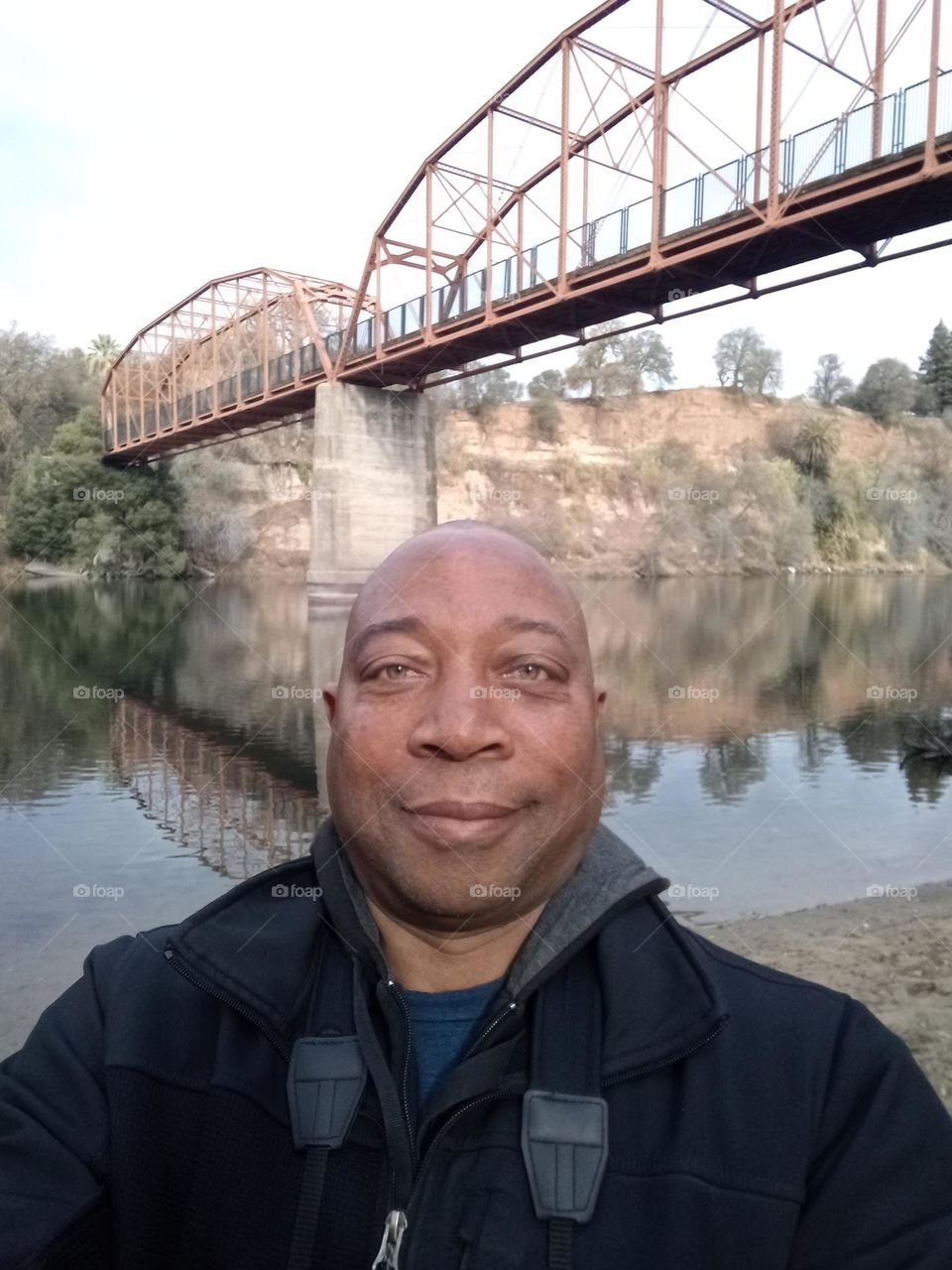 Self-portrait of a hiking under a red foot bridge in the early morning