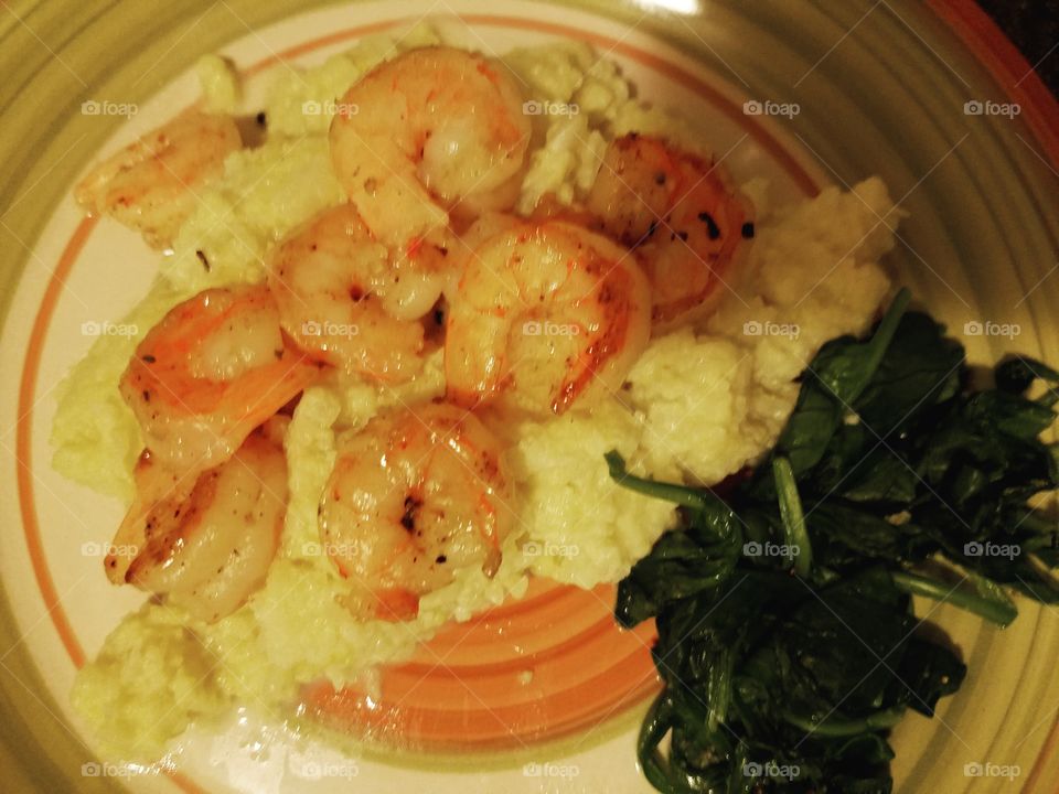 Cauliflower mashed topped with shrimp and gravy with a side of baby spinach.