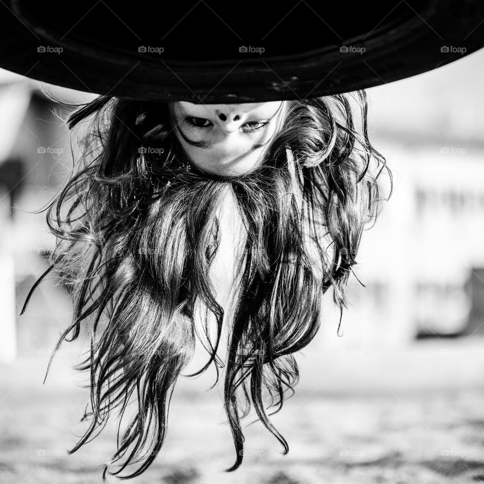 Child playing looking under swing long hair hanging down