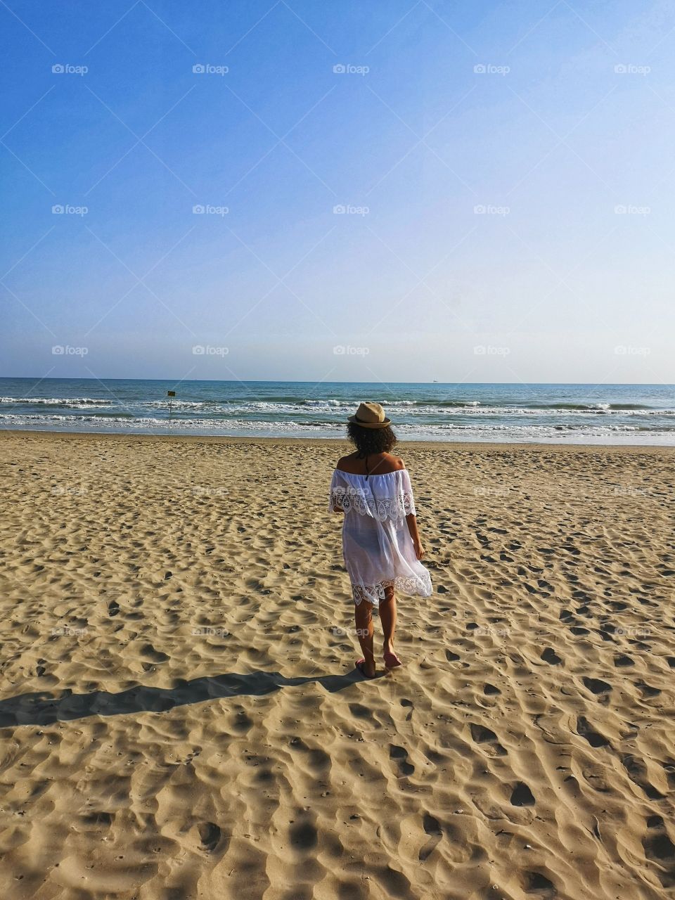 Lonely woman, from behind, looks at the sea and meditates