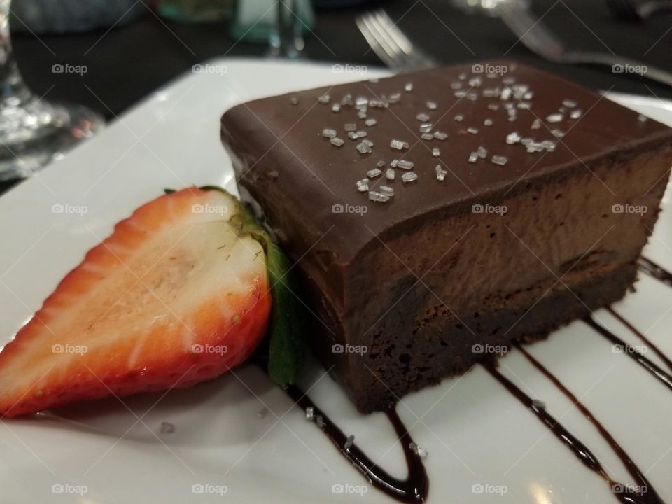 Decadent flourless chocolate mousse cake sprinkled with sea salt, garnished with a strawberry, perfect way to finish a meal 