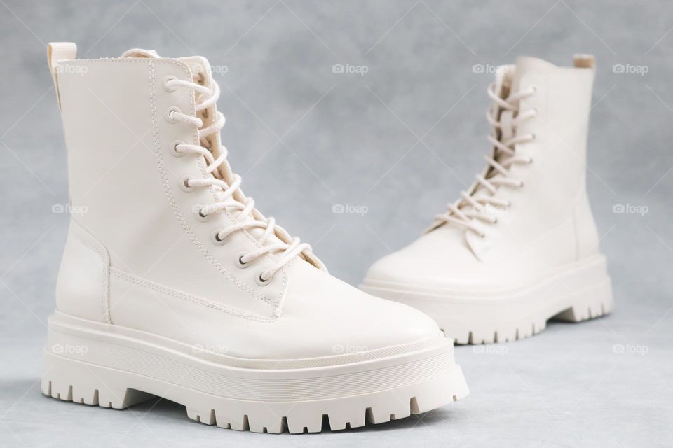 White Martens brand lace-up shoes standing on a light gray cement background,side view. The concept of fashionable women's shoes.