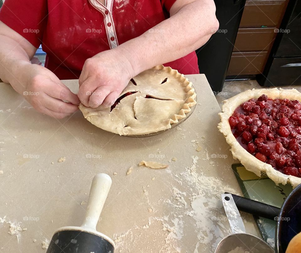 A woman fluting a cherry pie crust