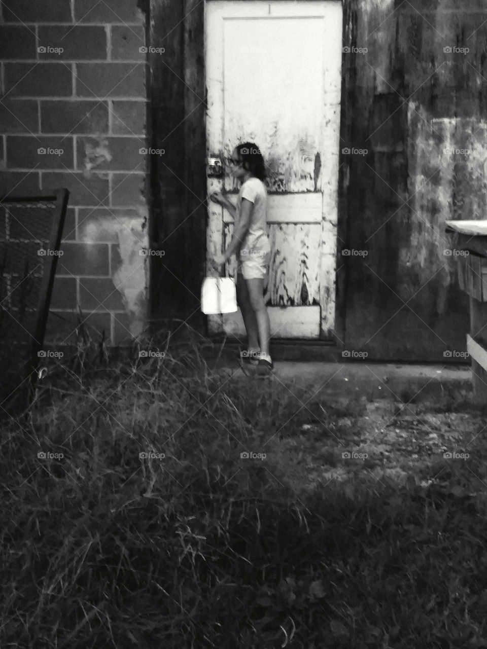 Little girl tries to get into an old shack in an alleyway to no avail.