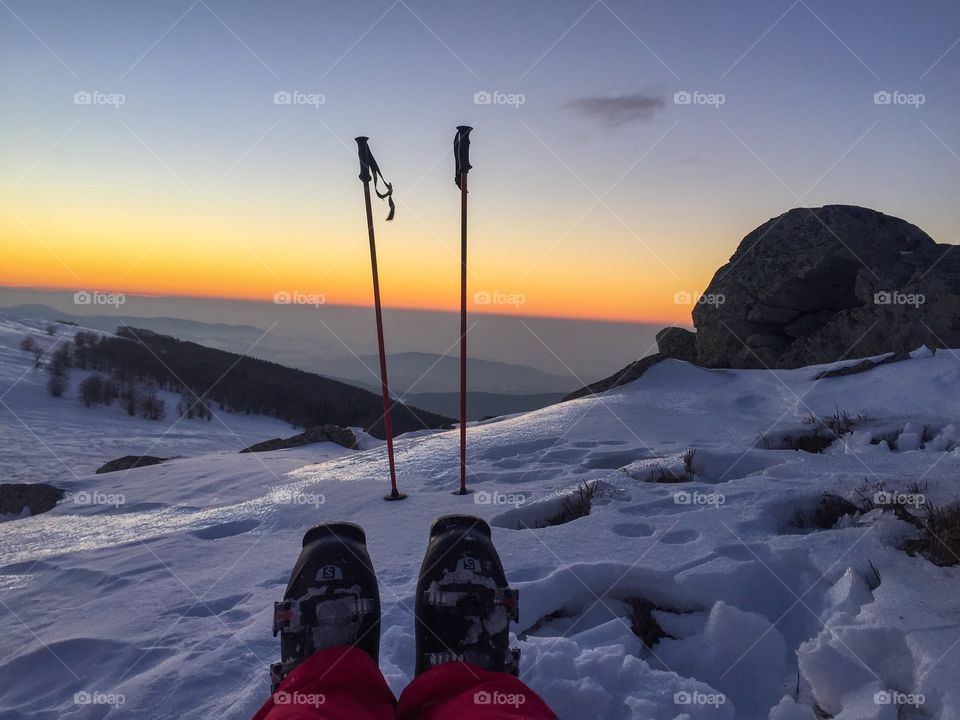 View of ski boots and ski poles at sunset