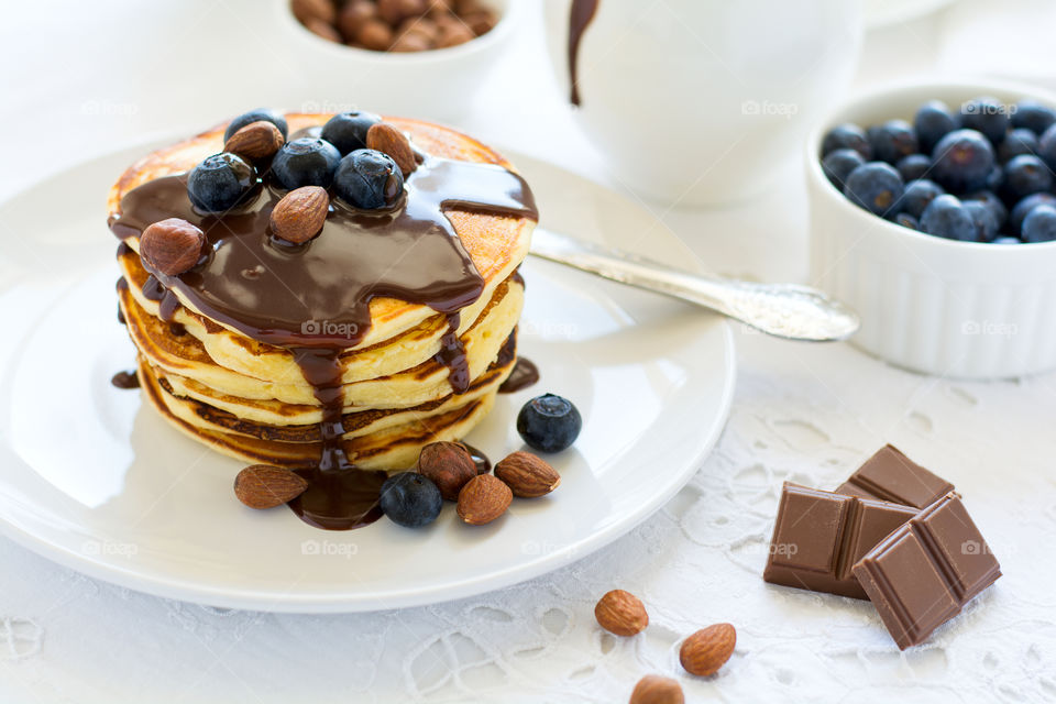 Stack of pancakes with chocolate sauce, blueberry and nuts. Healthy breakfast concept